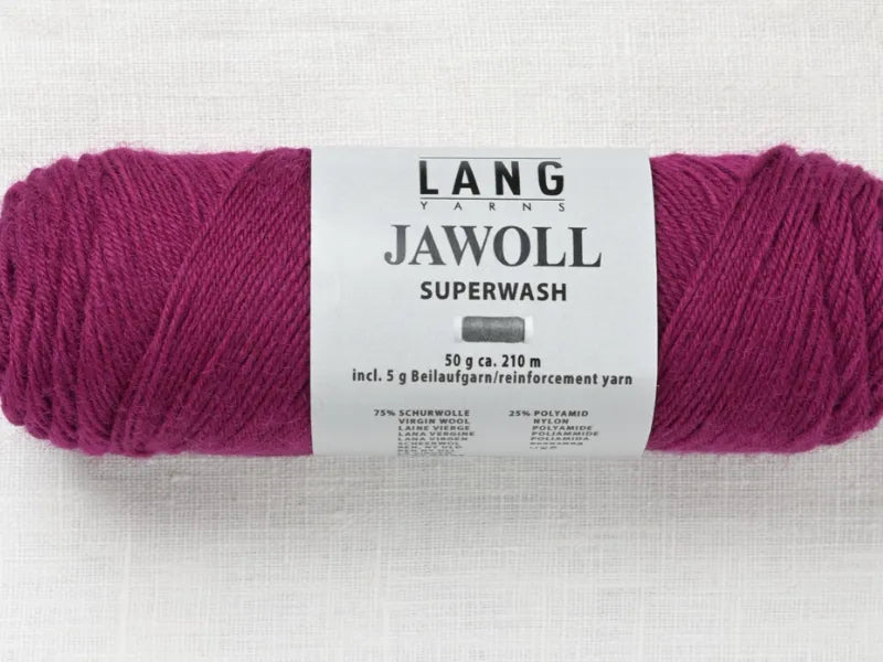 A skein of Timo sukka ohje fingerin ja Lang jawoll in magenta lies on a white fabric, its label showing 50g weight, 210m length, and fiber content—ideal for neulontaohje or Timo sukka ohje knitting projects.