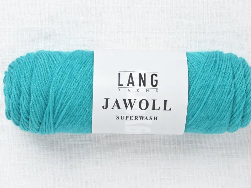 A skein of turquoise Timo sukka ohje fingerin ja Lang jawoll yarn with a white LANG YARNS JAWOLL SUPERWASH label lies on a light textured surface—ideal for your next neulontaohje or knitting project.