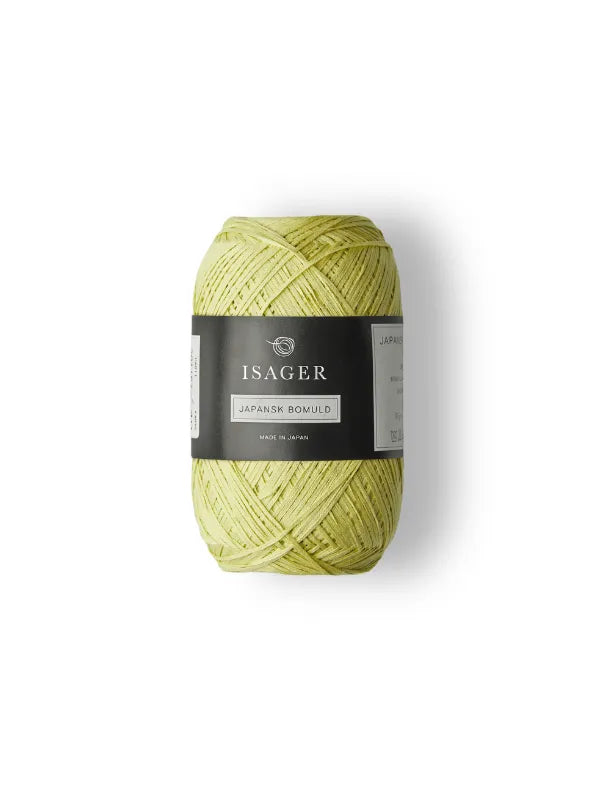 A skein of pale yellow Isager Japansk Bomuld with a black label sits on a white background—ideal for creating light, airy summer knits.