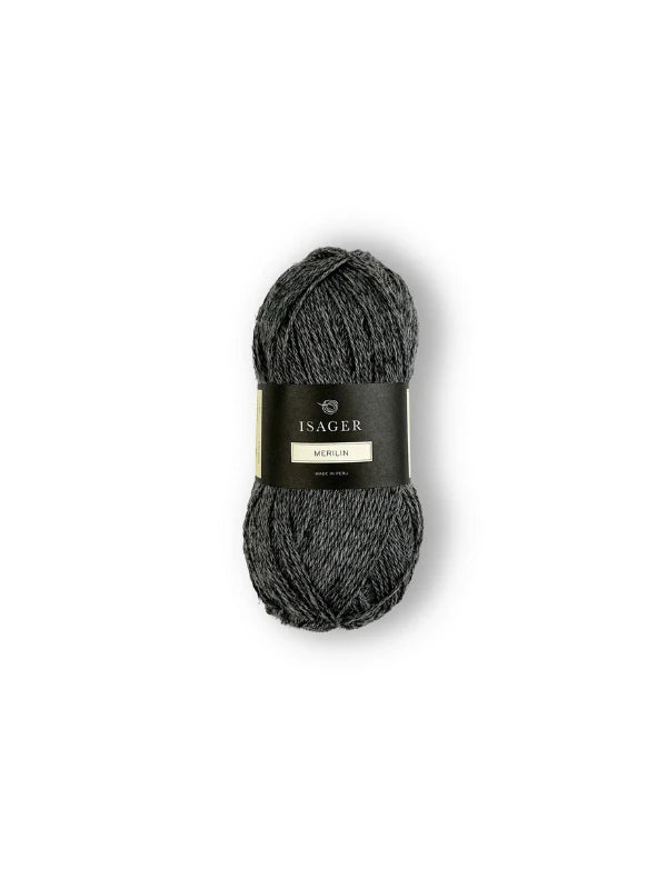 A skein of dark gray Isager Merlin yarn with a black and gold label is displayed against a plain white background.