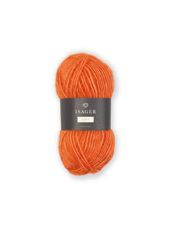 A skein of bright orange Isager Soft yarn, featuring a black band label at the center, is displayed on a plain white background.
