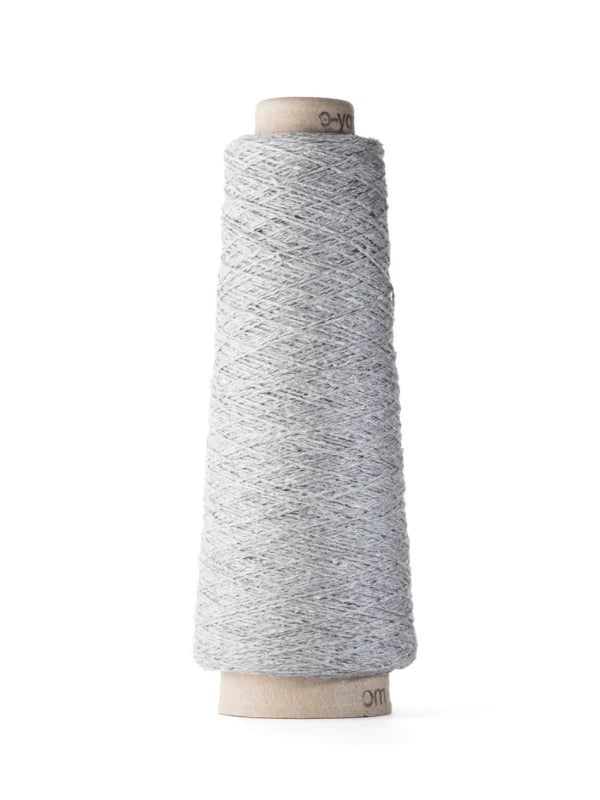A spool of Ito Kinu light gray 100% silkki japanilainen silkkilanka is tightly wound around a cardboard cone, standing upright against a white background—perfect for kesäneuleisiin.