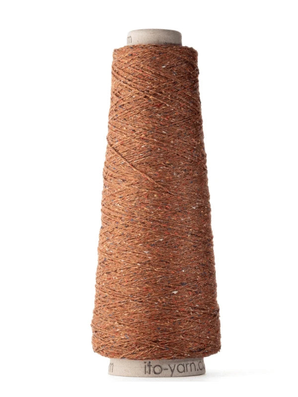 A large cone of Ito Kinu brown japanilainen silkkilanka with colorful flecks, tightly wound on a cardboard spool and standing upright on a white background—perfect for kesäneuleisiin.