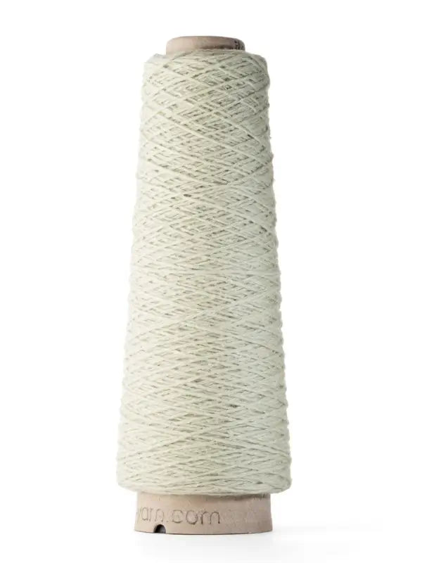 A tall cone of Ito Yarn Shimo, an elegant off-white blend of kierrätetty silkki and merinovillalanka, stands upright against a plain white background. The fine yarn is neatly wound around a cardboard core.