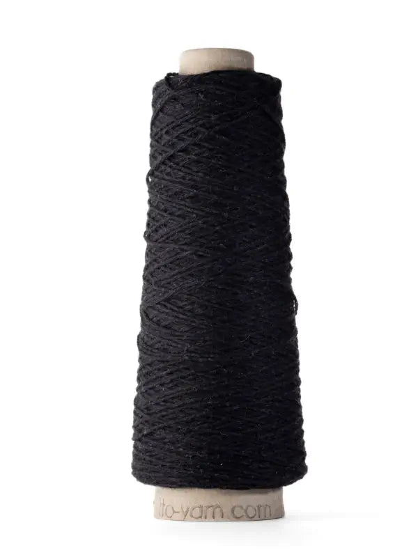 A spool of Ito Yarn Shimo in black stands upright against a white background. The yarn is tightly wound around a cardboard core, highlighting the fine texture characteristic of high-quality fibers.
