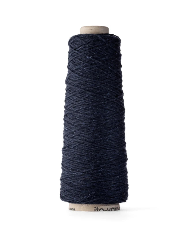 A spool of Ito Yarn Shimo in dark navy blue, made from kierrätetty silkki and merinovillalanka, is wound around a tall, cylindrical cardboard core and stands upright against a white background.