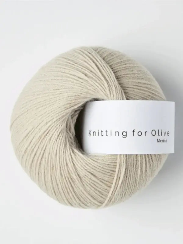 A ball of light beige Knitting for Olive Merino yarn with a white label rests on a plain white background. This luxurious merino wool is Öko-Tex certified, ensuring both safety and quality.