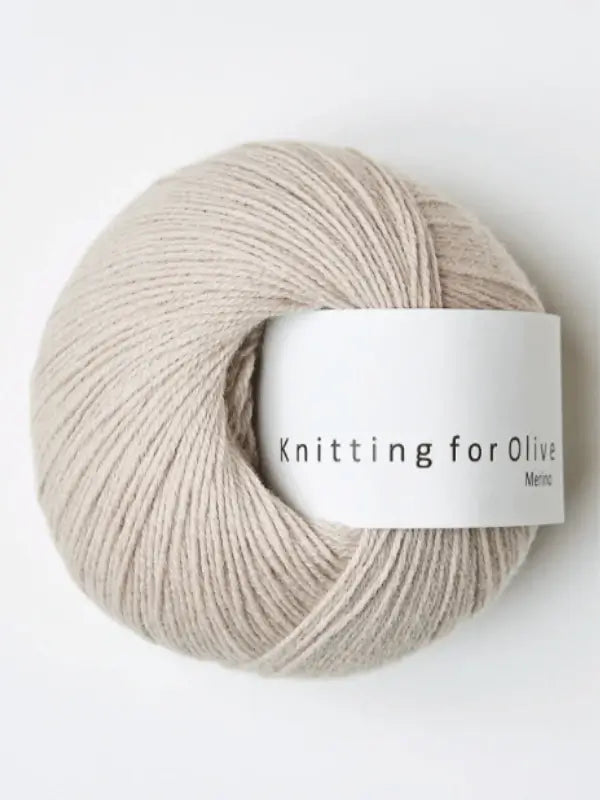 A ball of Knitting for Olive Merino yarn, light beige in color with a white label, is shown against a plain white background.
