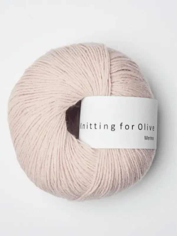 A skein of pale pink Knitting for Olive Merino yarn with a white label, Öko-Tex certified, is displayed on a plain white background.