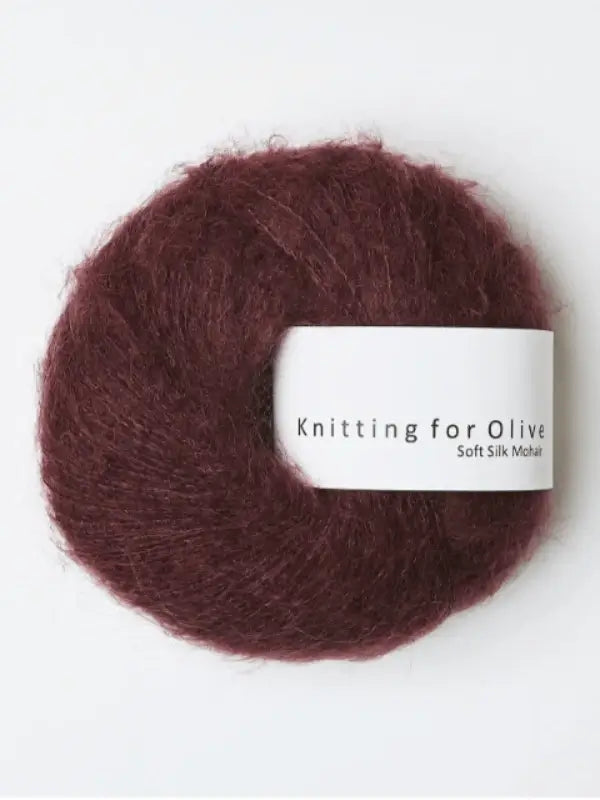 A skein of Knitting for Olive Soft Silk Mohair yarn in deep burgundy is displayed against a plain white background, emphasizing its luxurious blend of silk and mohair fibers.