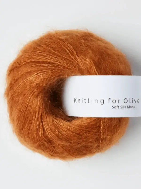 A ball of fluffy, rust-colored Knitting for Olive Soft Silk Mohair yarn—this vastuullinen mohair blend combines the luxurious softness of kid mohair with the delicate sheen of silk, set against a plain white background.