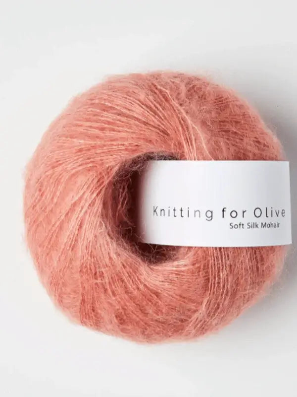A ball of soft, pink Knitting for Olive Soft Silk Mohair yarn with a white label, displayed on a plain white background.