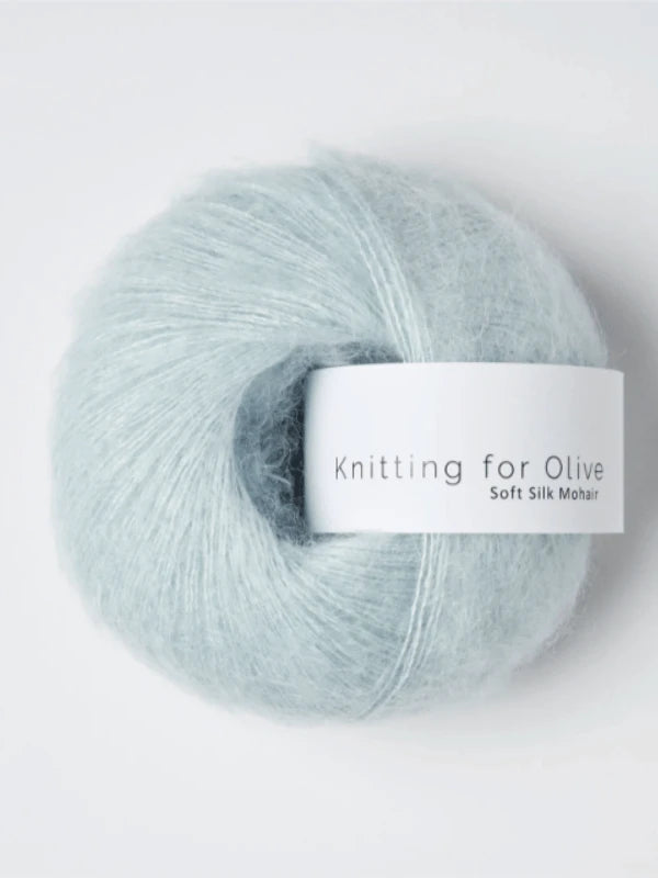 A pale blue ball of Knitting for Olive Soft Silk Mohair, made from luxurious kid mohair and silk and featuring a white label wrapped around the center, is displayed on a plain white background.