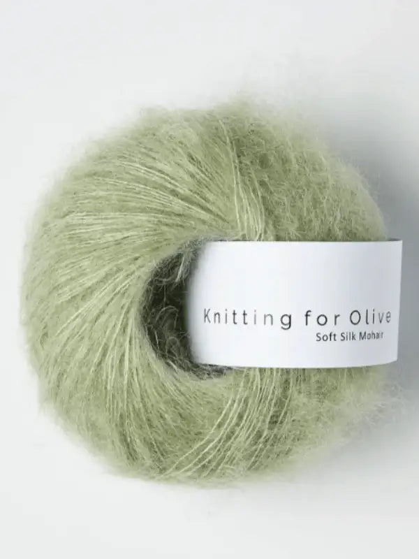 A ball of light green Knitting for Olive Soft Silk Mohair yarn with a white label. The yarn looks soft and fuzzy, crafted from vastuullinen mohair and luxurious silkki lanka for an exceptionally gentle touch.