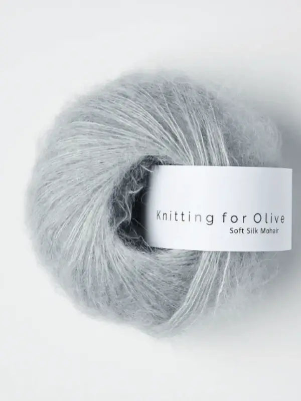 A skein of Knitting for Olive Soft Silk Mohair yarn, made from light gray premium kid mohair that meets the Responsible Mohair Standard, is shown as a soft and fluffy ball against a plain white background.