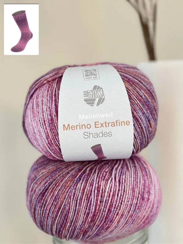 Two skeins of Lana Grossa Meilenweit 100 Merino extrafine Shades yarn in pink, purple, and white, with a small image of a knitted sock shown in the top left corner.