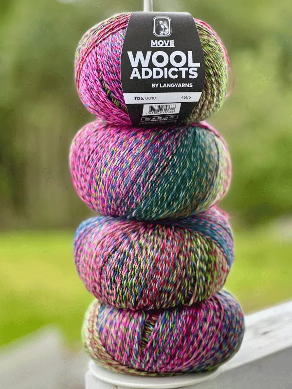 Four colorful balls of Lang Yarns Wool Addicts Move 4 variegated sukkalanka, mostly pink with green, yellow, and blue tones, are stacked outdoors. The top ball has a label. The blurred background features greenery.