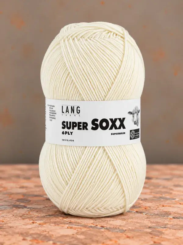 A ball of cream-colored Lang Yarns Super Soxx 6 ply – kestävä sukkalanka villasta yarn with a product label featuring a sheep illustration and text.