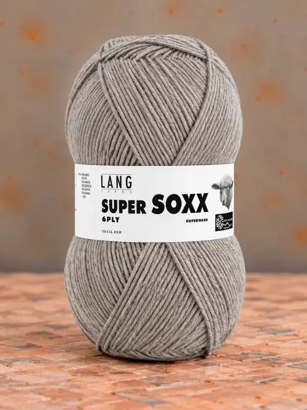 A ball of beige Lang Yarns Super Soxx 6 ply – kestävä sukkalanka villasta yarn with a label reading Super Soxx 6ply.
