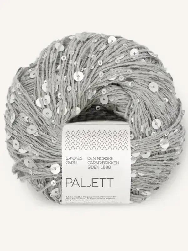 A ball of light gray Sandnes Garn Paljett yarn embellished with scattered silver sequins, wrapped in a white paper label.