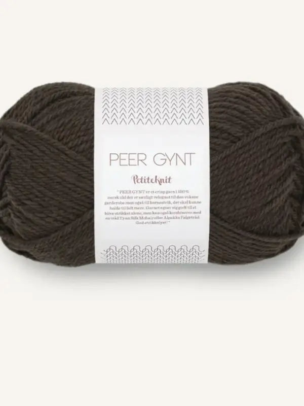 A skein of dark brown yarn labeled Sandnes Garn Peer Gynt, with a white paper band around the center featuring text and simple decorative patterns. This soft, 100% high-quality norjalainen villa yarn is part of the beloved Sandnes Garn Peer Gynt collection, perfect for timeless knitting projects.