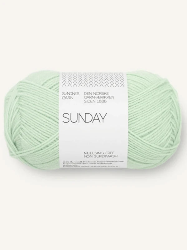 A skein of Sandnes Garn Sunday in light mint green, a fingering-weight merino wool yarn with a white label marked "mulesing-vapaa merinovilla," featuring Norwegian text and subtle zigzag designs.