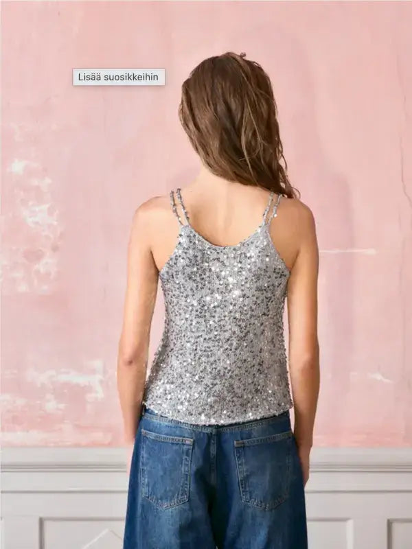 Back view of a person wearing a silver sequined Sandnes Garn Nia Top – paljettitopin neulesetti with double spaghetti straps and blue jeans.