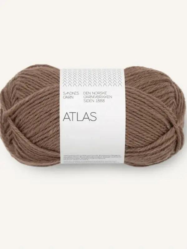 A ball of Sandnes Garn Atlas brown yarn with a white label displaying the brand name and other details in Norwegian, made from norjalainen karitsanvilla, set against a plain, light background.