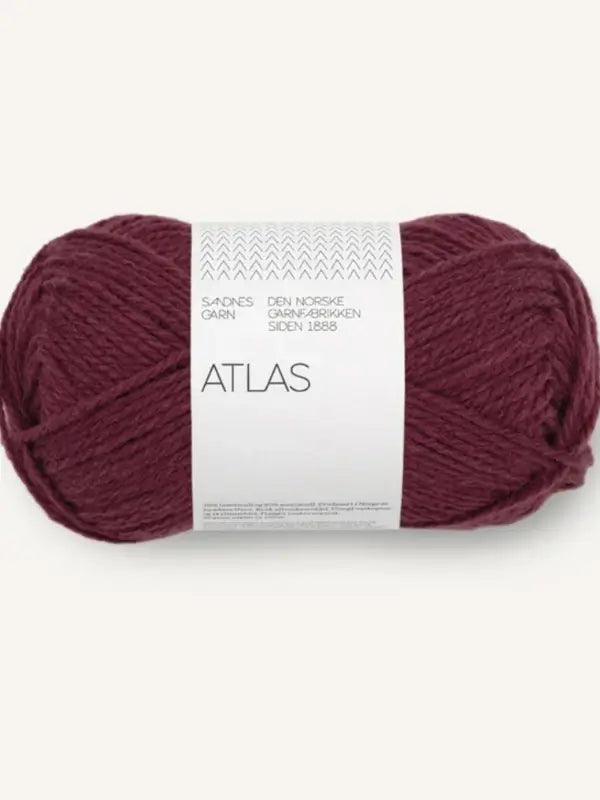 A skein of Sandnes Garn Atlas yarn in maroon, crafted from soft Norwegian lamb’s wool (norjalainen karitsanvilla), features white packaging with black text and subtle pattern accents.