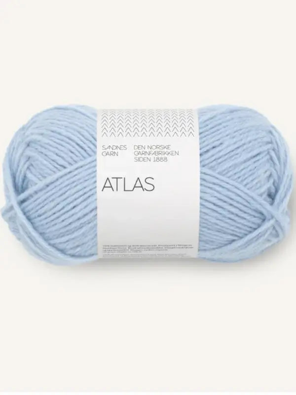 A skein of light blue Sandnes Garn Atlas yarn, made from norjalainen karitsanvilla merino wool, wrapped with a white paper band at the center featuring product information.
