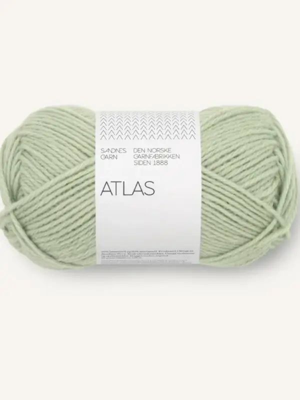 A skein of light green yarn labeled Sandnes Garn Atlas, featuring additional text in Norwegian on a white band and displayed against a plain, light background. This soft yarn is made from Norwegian lambswool (norjalainen karitsanvilla), offering both quality and comfort for your knitting projects.