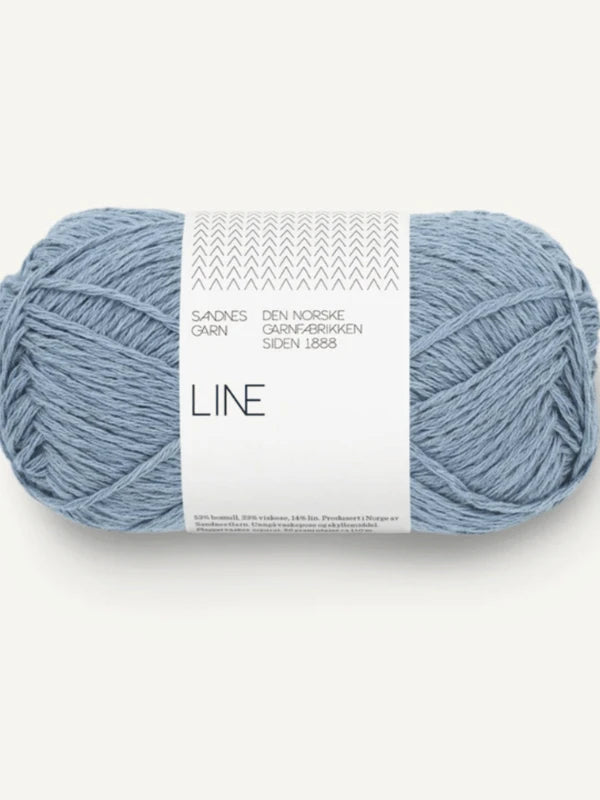 A skein of Sandnes Garn Line in light blue, featured in PetiteKnit Anker’s Summer Shirt, comes with a white label displaying Norwegian text and a chevron design—ideal for knitting stylish summer shirts.