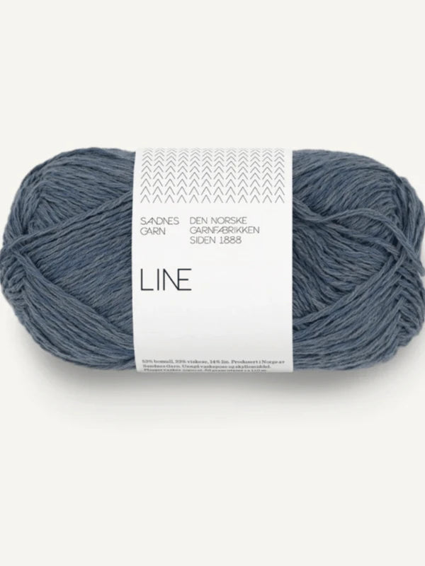 A skein of blue-grey Sandnes Garn Line yarn, labeled “Sandnes Garn, Den Norske Garnfabrikken siden 1888, LINE,” comes with the PetiteKnit Anker’s Summer Shirt pattern—perfect for your next knitting project.