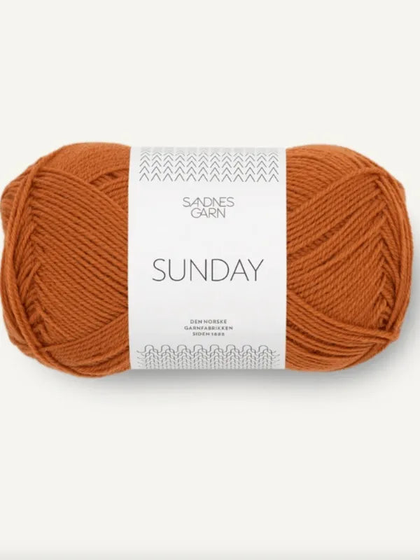 A rust orange ball of Sandnes Garn Sunday merino wool yarn with a white and gray band, featuring a modern design and labeled as mulesing-free.