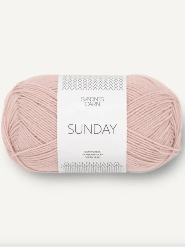 A skein of light pink yarn with a white label reading Sandnes Garn Sunday is displayed against a plain background, representing the PetiteKnit Anker’s Sweater My Size Neuleohje ja Sandnes Garn Sunday product.