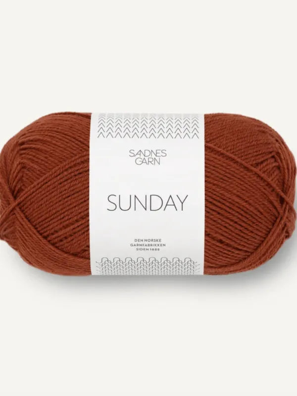 A skein of reddish-brown Sandnes Garn Sunday, fingering-weight mulesing-free merino wool yarn, with a white minimalist-patterned label.