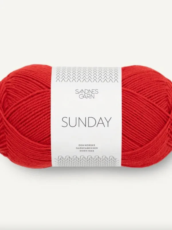 A skein of bright red Sandnes Garn Sunday, a fingering-weight yarn made from mulesing-free merino wool, with white packaging featuring minimal black text and a simple geometric pattern.