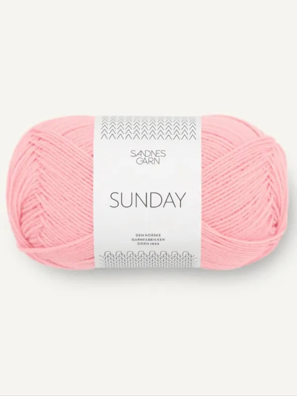 A skein of light pink Sandnes Garn Sunday fingering weight yarn, made from mulesing-free merino wool, with a white and gray label, shown against a light background.