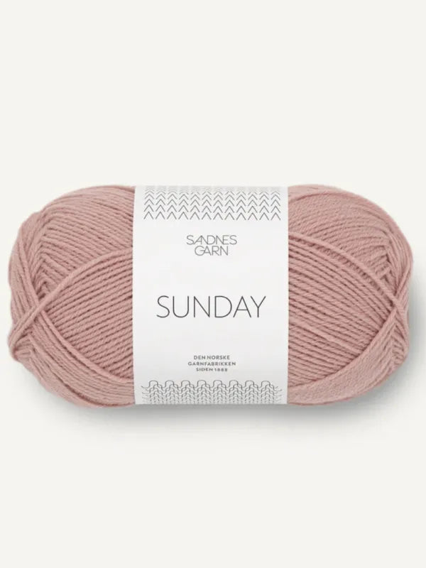 A skein of Sandnes Garn Sunday in light dusty pink features a white minimalist label. Made from ethical, mulesing-free merino wool, this fingering-weight yarn offers soft texture and quality design.