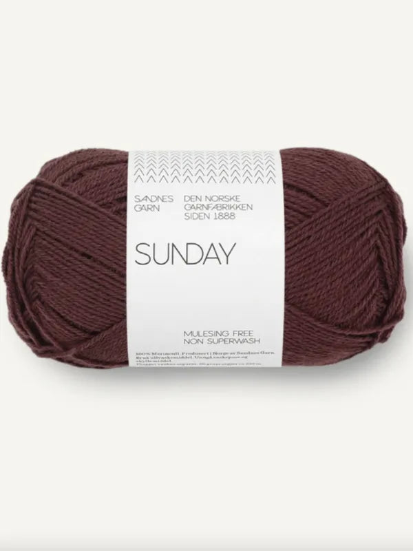 A skein of Sandnes Garn Sunday yarn in dark brown, made from mulesing-free merino wool and non-superwash, fingering weight, is shown against a plain background.