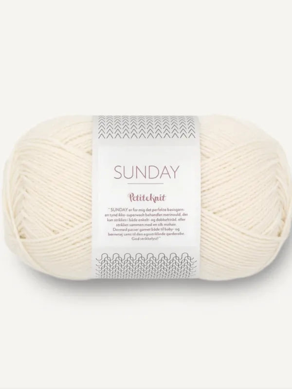A skein of off-white Sandnes Garn Sunday merino yarn is displayed against a plain background, featuring simple decorative patterns on the mulesing-free label.