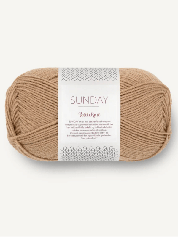 A ball of light brown Sandnes Garn Sunday yarn by PetitKnit, mulesing-free and perfect for soft knitting projects, wrapped in a white band with text and patterns.
