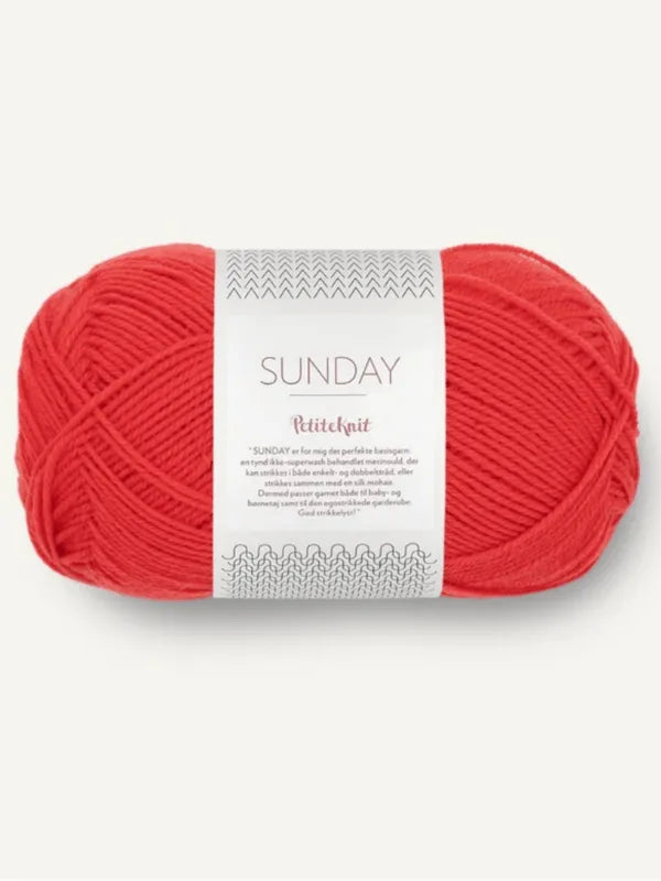 A skein of bright red Sandnes Garn Sunday merino wool yarn, labeled "Sandnes Garn Sunday," with white and gray packaging featuring knitting designs and "mulesing-vapaa" text in the center.