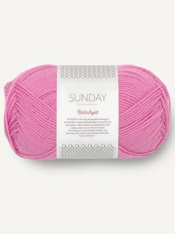 A skein of light pink Sandnes Garn Sunday fingering yarn labeled SUNDAY PetiteKnit, made from mulesing-free merino wool, with knitting patterns on the white label, displayed on a plain background.