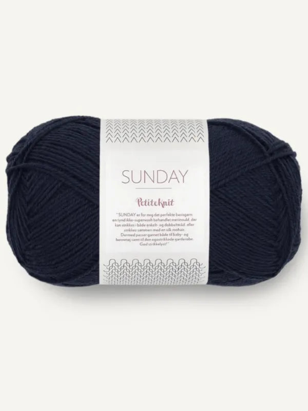 A skein of Sandnes Garn Sunday in dark navy blue, a fingering-weight, mulesing-free merino wool yarn with a white PetiteKnit label, shown against a plain light background.