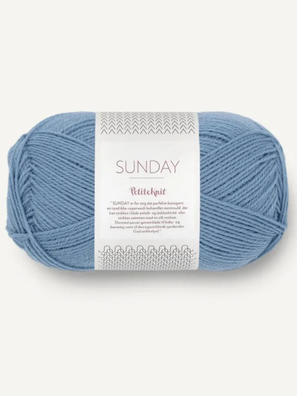 A skein of light blue Sandnes Garn Sunday yarn with a white label that includes the brand name and “mulesing-vapaa,” plus more details in smaller print.