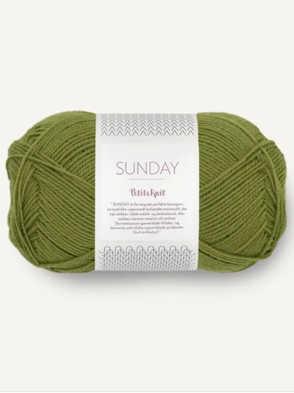A skein of green Sandnes Garn Sunday yarn, made from mulesing-free merino wool, features the Sunday PetiteKnit label with text and decorative patterns on a white paper band wrapped around this fingering-weight yarn.