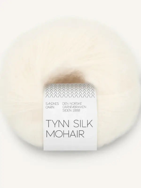 A ball of off-white Sandnes Garn Tynn Silk Mohair yarn, wrapped with a white label displaying black text and a chevron pattern at the top.
