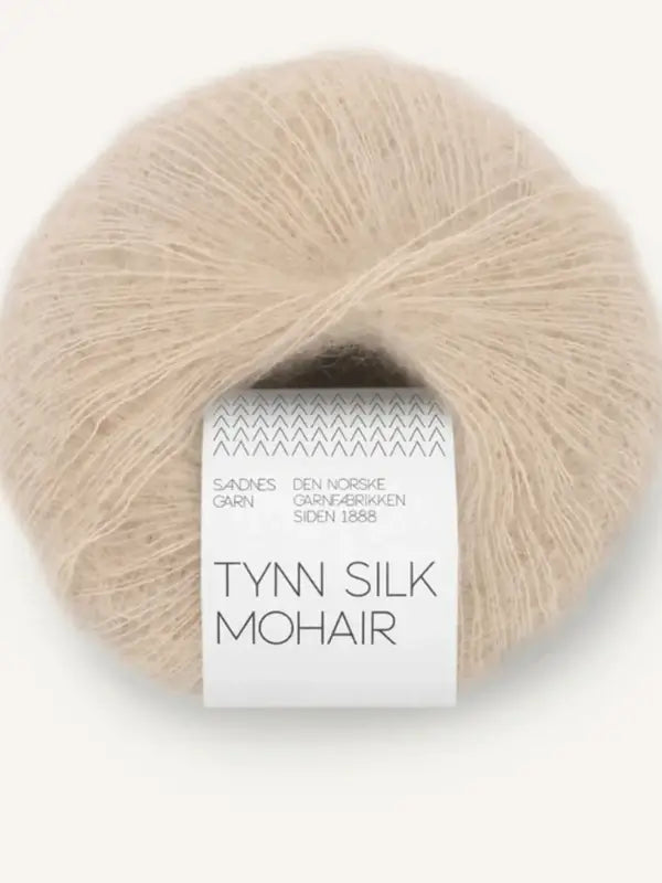 A beige ball of Sandnes Garn Tynn Silk Mohair yarn with a white label wrapped around it, featuring simple black text and a zigzag pattern at the top of the label.