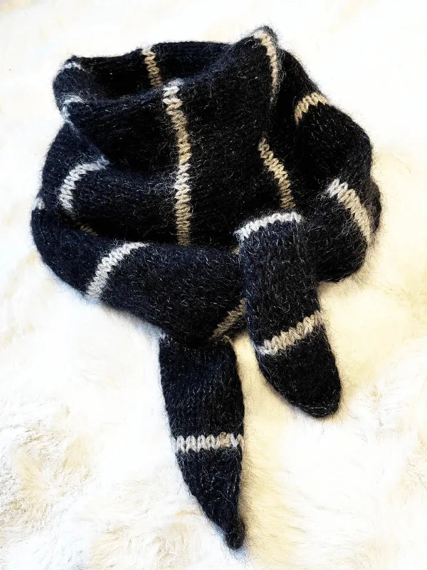 A fluffy black knitted scarf with white stripes, made from Knitting for Olive Merino and Soft Silk Mohair, features in the Somany huivi ohje PDF, coiled on a soft white surface.
